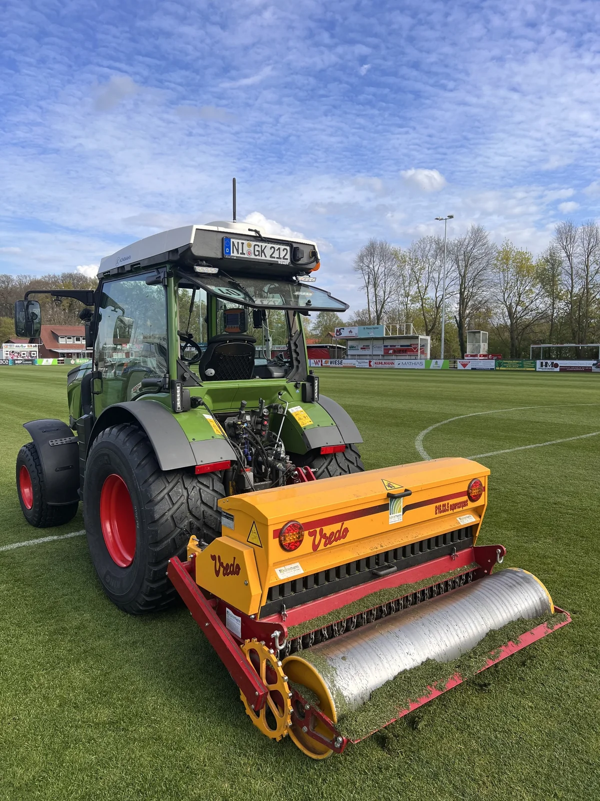 Vredo-Nachsaatgerät am Fendt-Traktor auf einem Naturrasensportplatz.