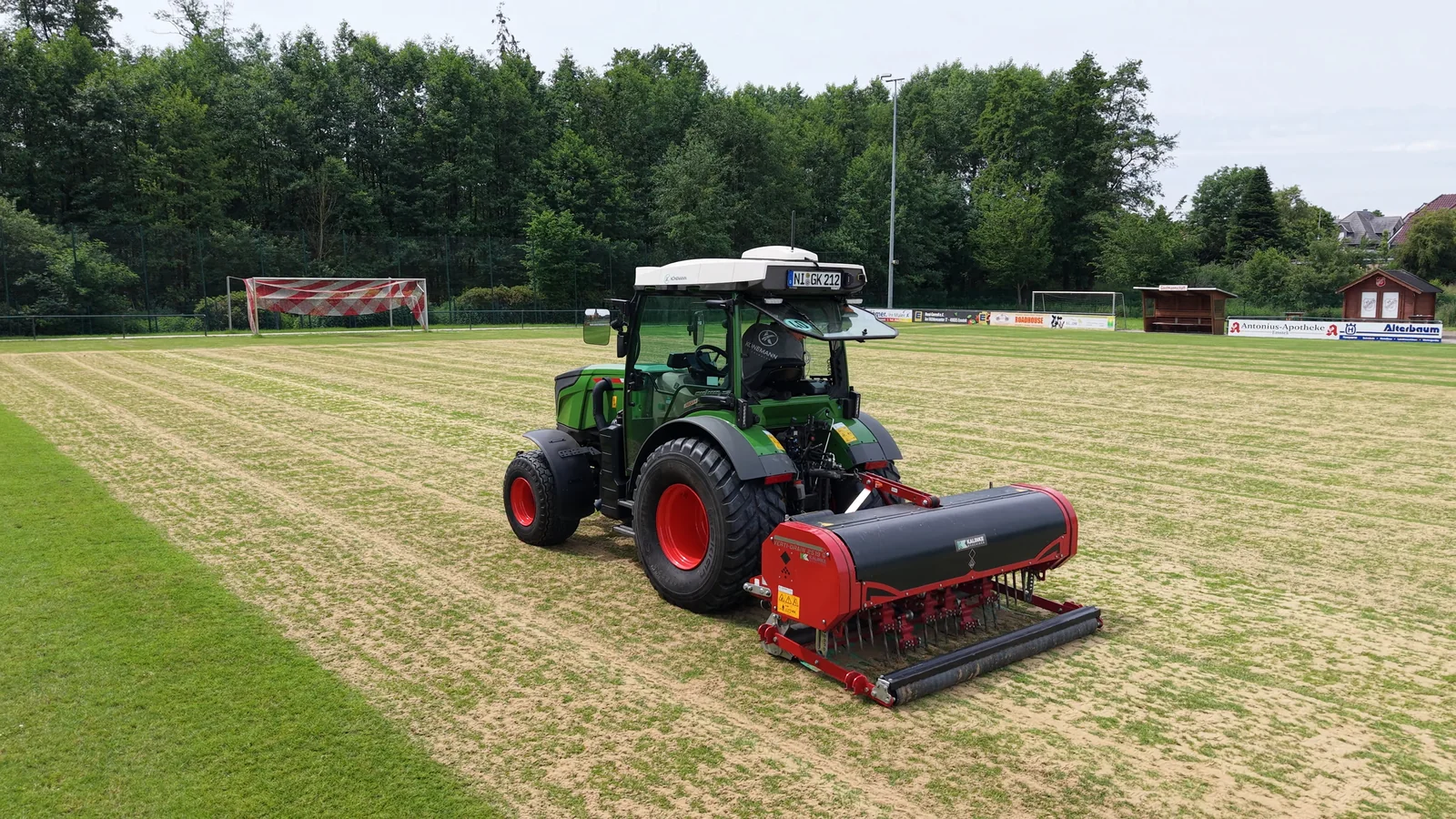 Fendt-Traktor mit VertiDrain bei der Bearbeitung eines Naturrasensportplatzes.