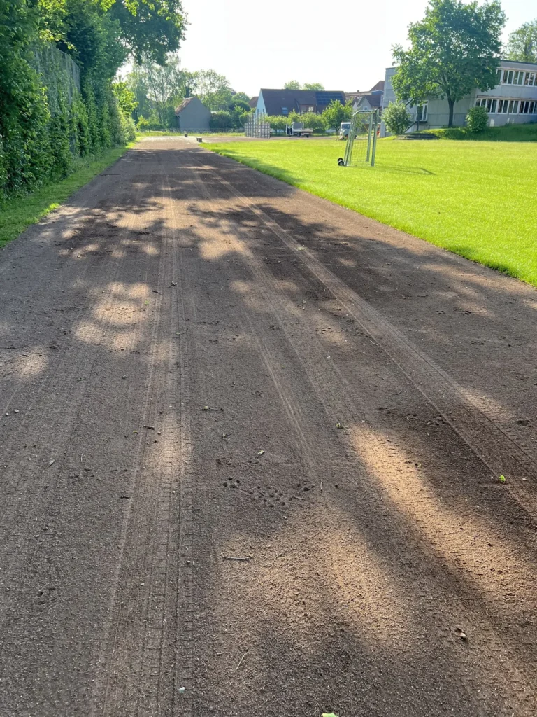 Bearbeitete Laufbahngerade entlang einer Grünfläche, mit sichtbaren Bearbeitungsspuren.
