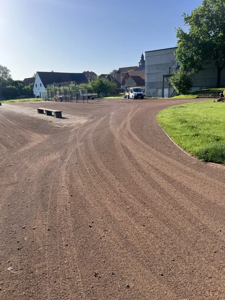 Aufgearbeitete Tennenfläche mit deutlich sichtbarer Oberfläche und geschwungenem Übergang zum Rasen.