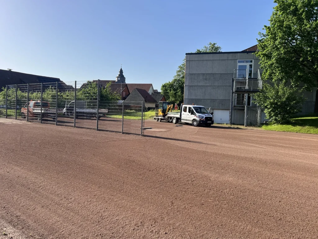 Übersicht der aufgearbeiteten Tennenfläche mit Toren und angrenzenden Gebäuden.